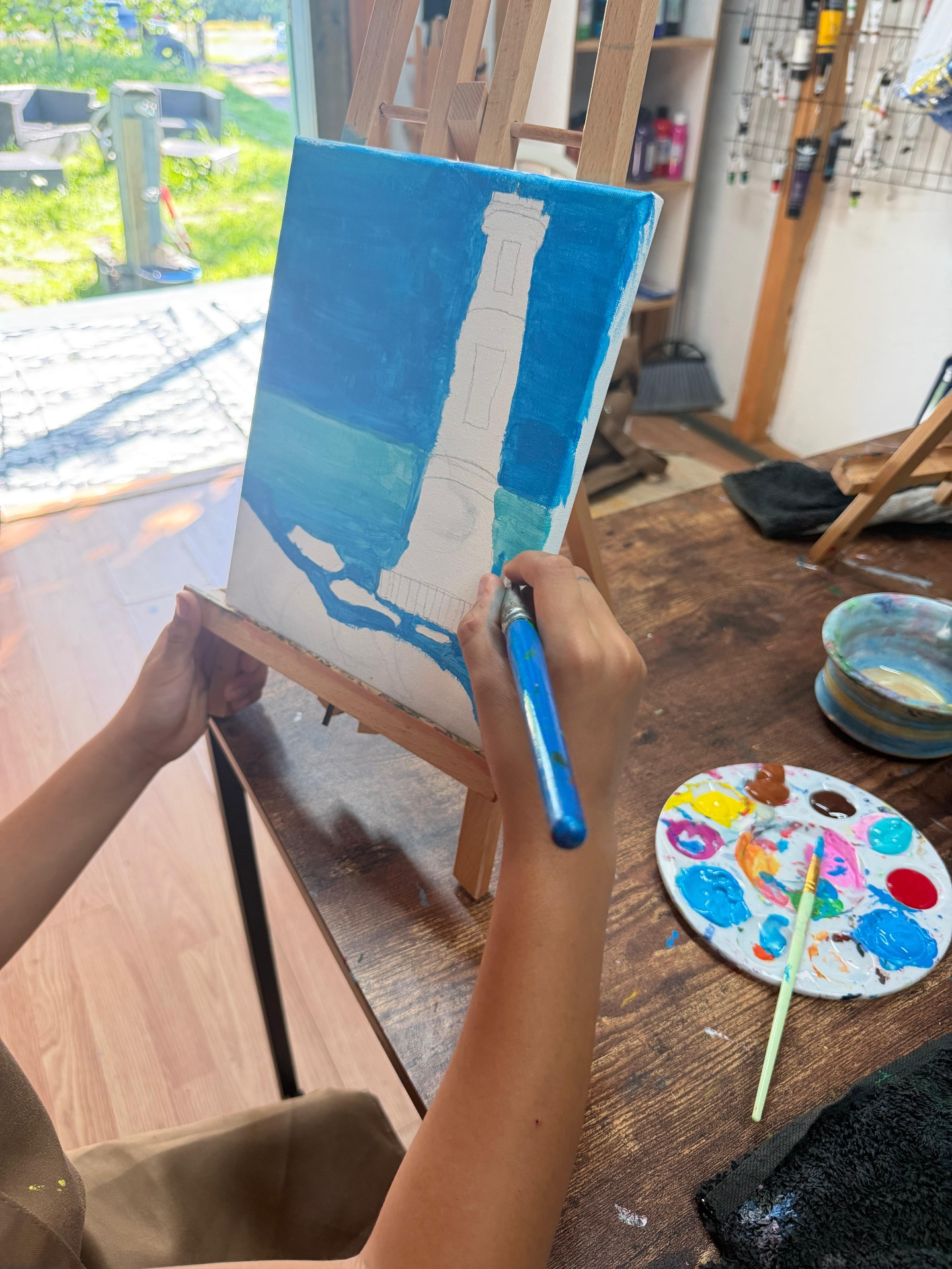 Young artist painting a lighthouse on an easel