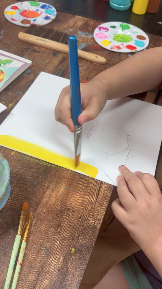 Child starting a painting with yellow brushstrokes