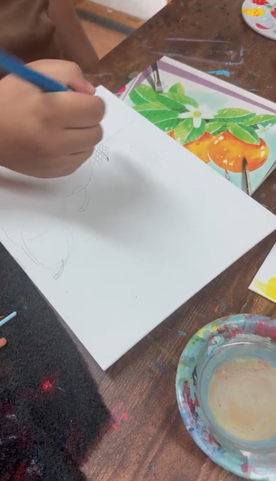 Child sketching an orange still life