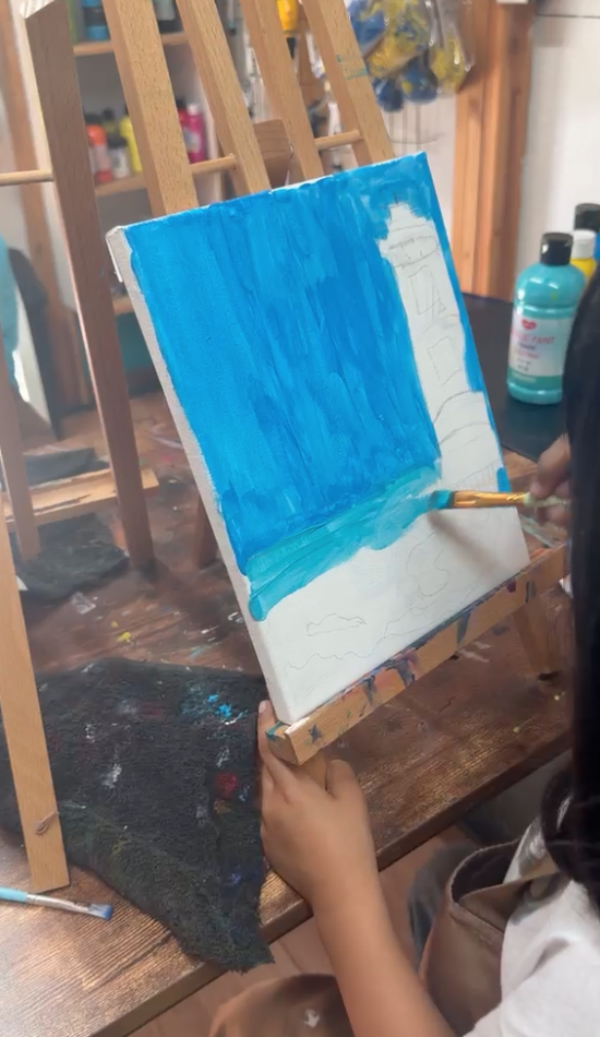 Young artist blocking in blues for a lighthouse scene