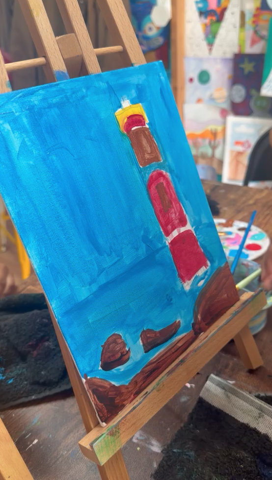 Red and yellow lighthouse painting on easel